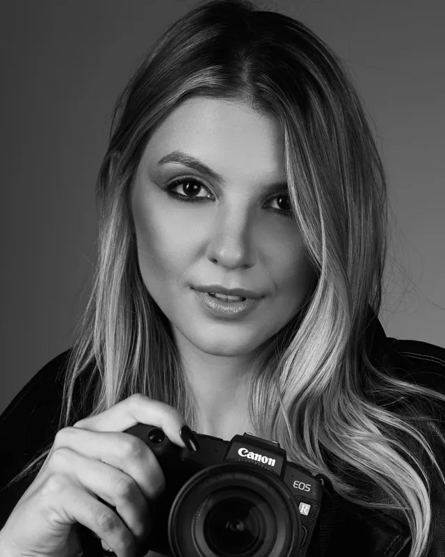 Carol Muneron, fotógrafa em Curitiba, segurando a câmera, retrato em preto e branco